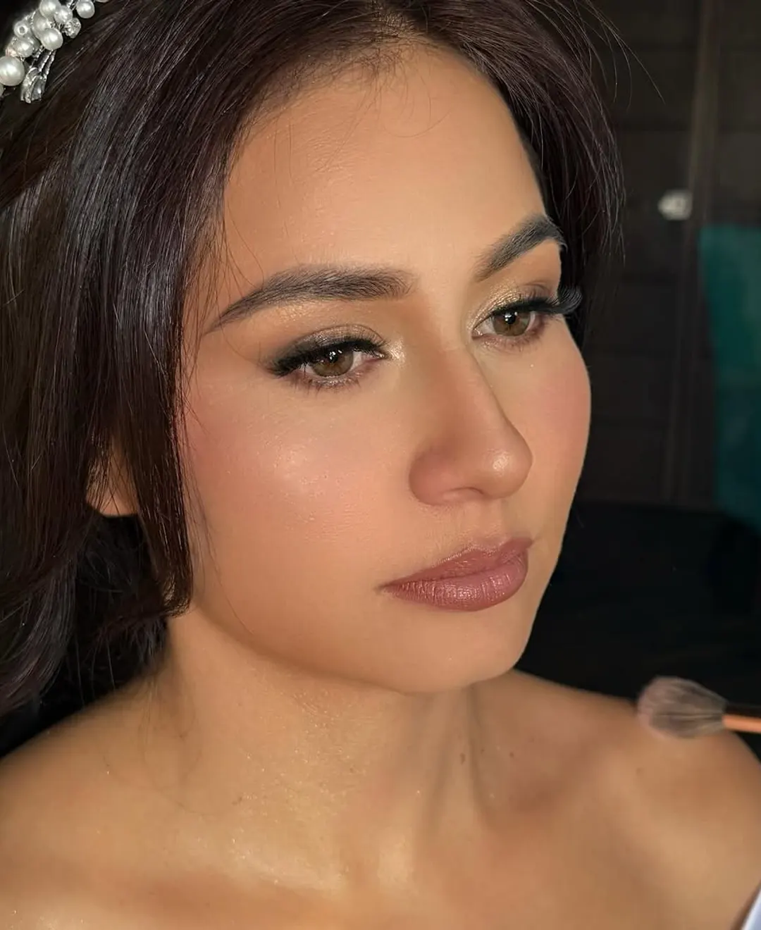 Novia en proceso de maquillaje con tiara de perlas — preparación previa a la ceremonia