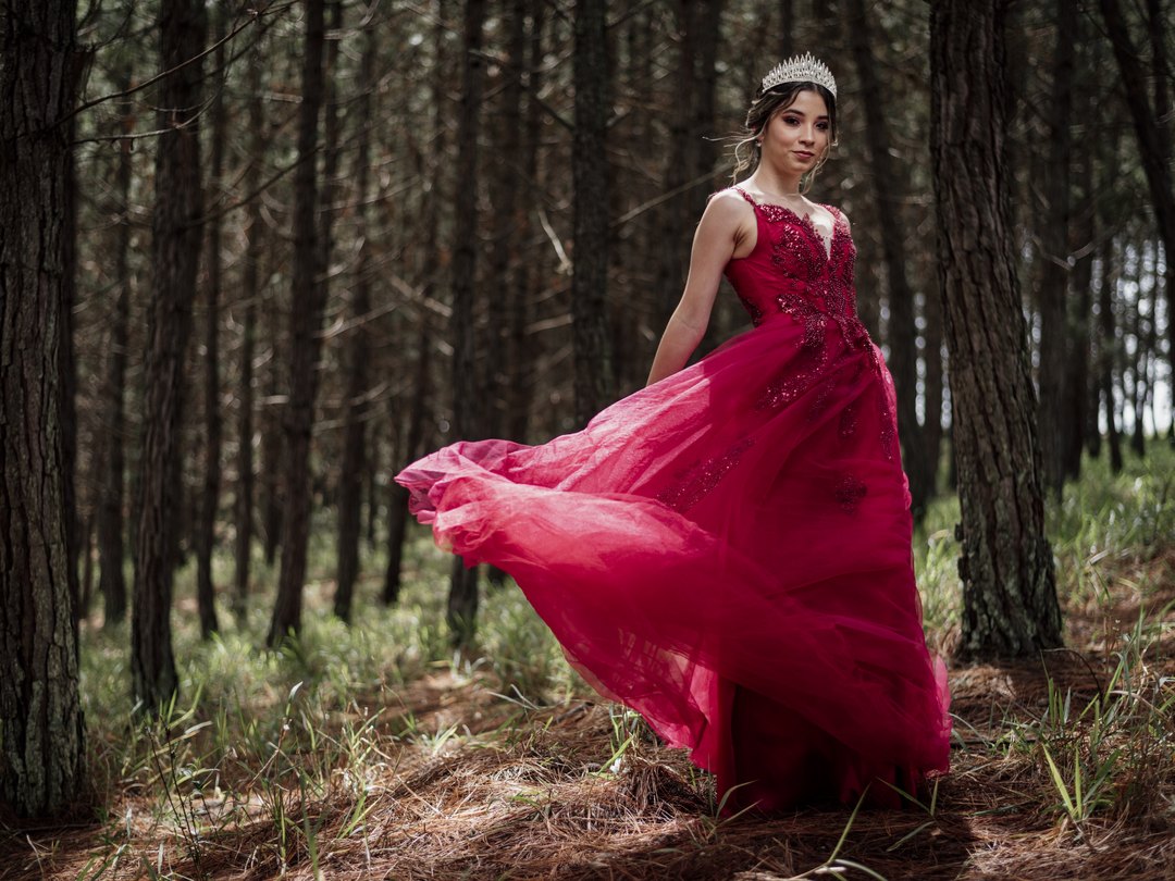 Quinceañera con vestido rojo y tiara en sesión editorial