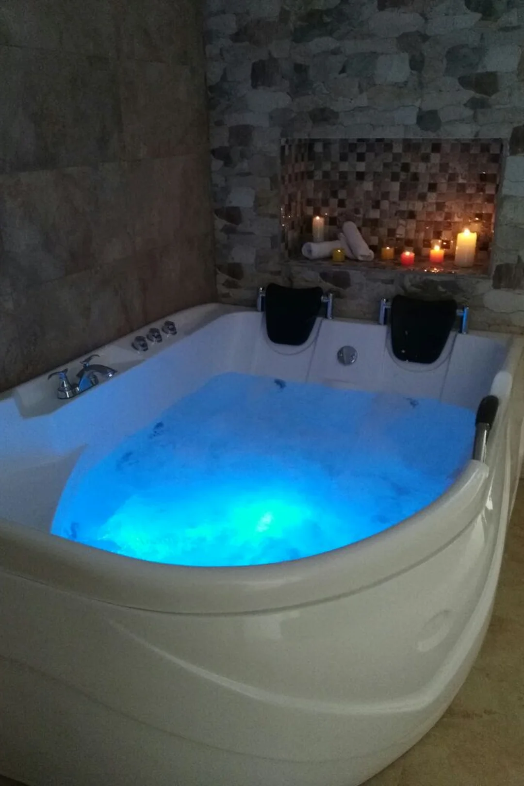 Jacuzzi en uso con luces azules y velas — ambiente de relajación nocturna